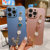 a woman holding up two iphone cases with charms