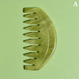 there is a green comb with a long handle on a green surface