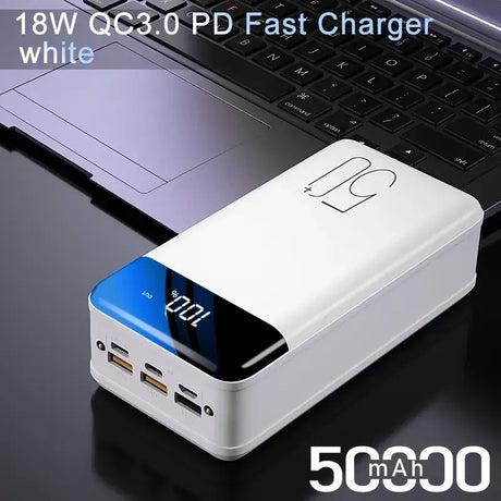 A laptop with a white power bank on top of it