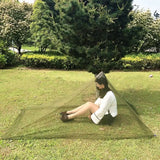 a woman sitting on the grass in a mosquito net