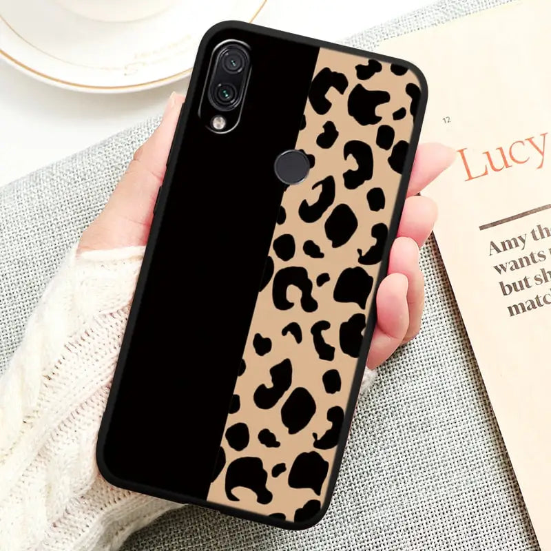 a woman holding a phone case with a black and white leopard print