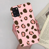 a woman holding a pink phone case with brown spots on it
