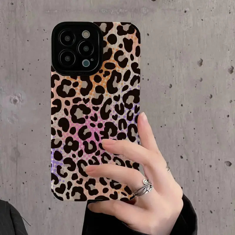 a woman holding up a phone case with a leopard print