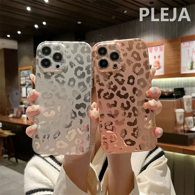 a woman holding up two iphone cases with leopard print