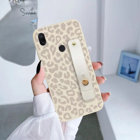 a woman holding a phone case with a leopard print