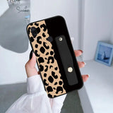 a woman holding up a phone case with a black and white leopard print