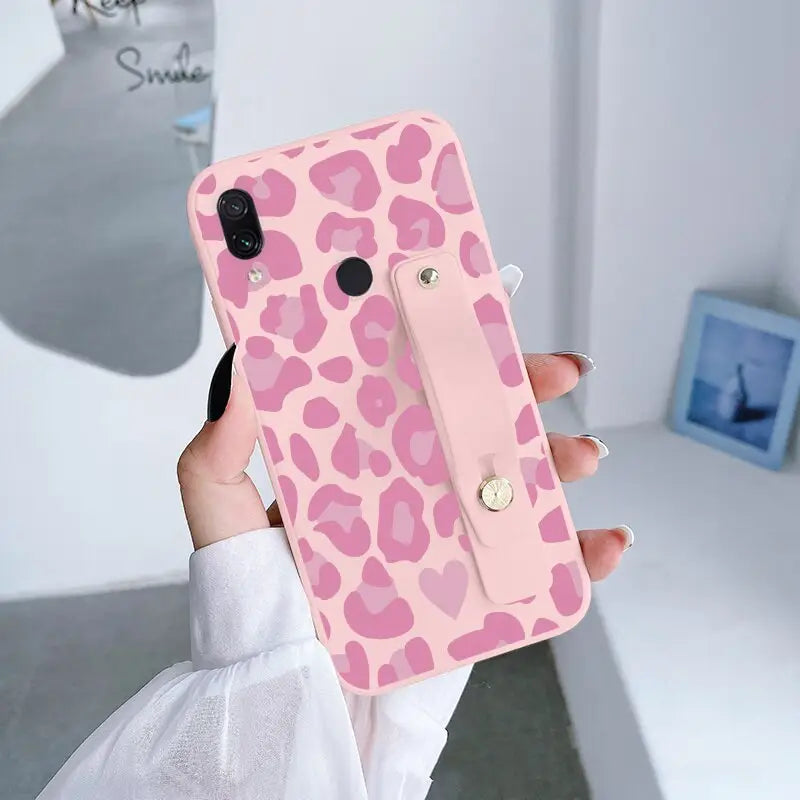 a woman holding a pink phone case with a pink leopard print