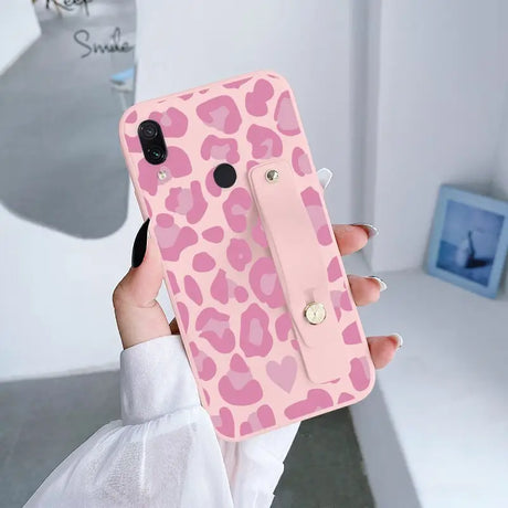 a woman holding a pink phone case with a pink leopard print