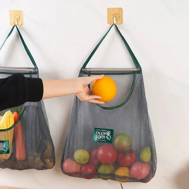 two mesh bags hanging on a wall with fruit in them