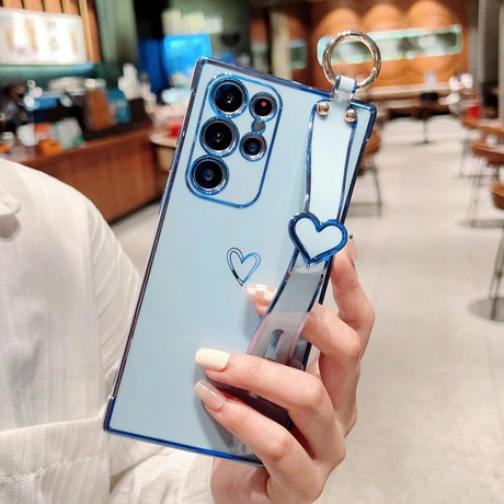 Light blue smartphone with multiple cameras and a heart-shaped charm on a wrist strap.