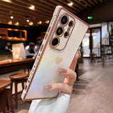 A light-colored smartphone with a glittery gold heart design and a multi-camera system.