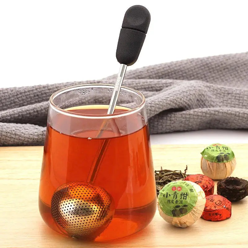 a glass cup filled with tea and a tea strainer