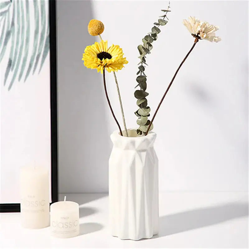 a vase with flowers in it next to a candle