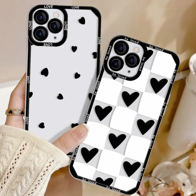 a woman holding up a phone case with black hearts on it