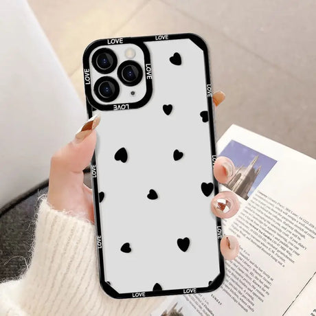 a woman holding a phone case with black hearts on it