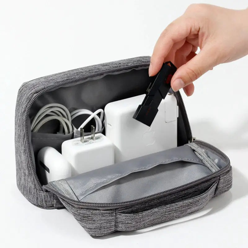 a hand holding a charging cable in a gray bag