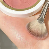 a person holding a brush and a bowl of blush
