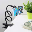 a phone holder on a desk next to a plant