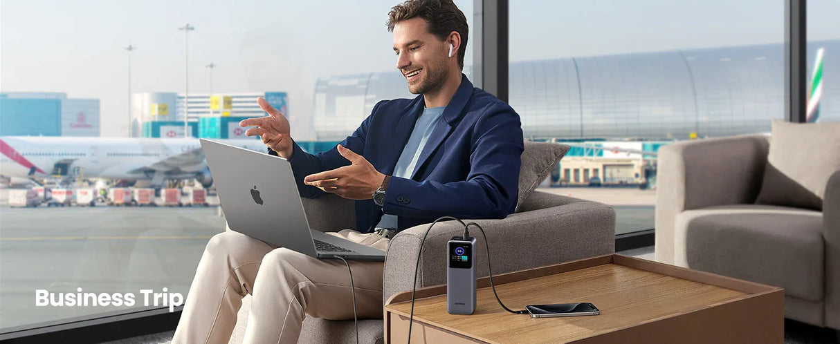 Man sitting on a couch using a laptop while holding a coffee cup.