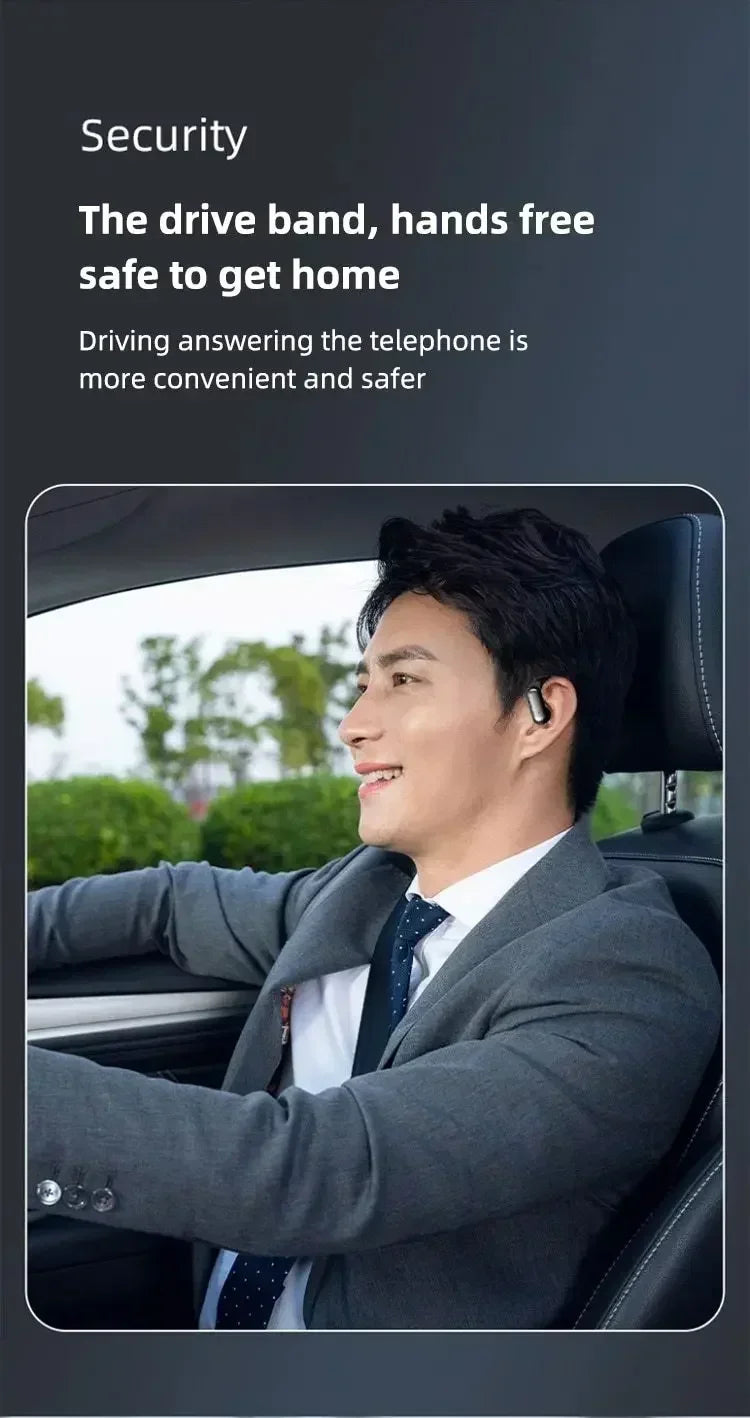 A man in a suit driving a car, wearing an in-ear Bluetooth headset.