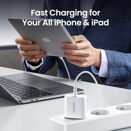 A man in a suit holding a tablet and charging an ipad