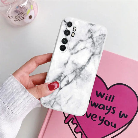 a woman holding a white marble phone case