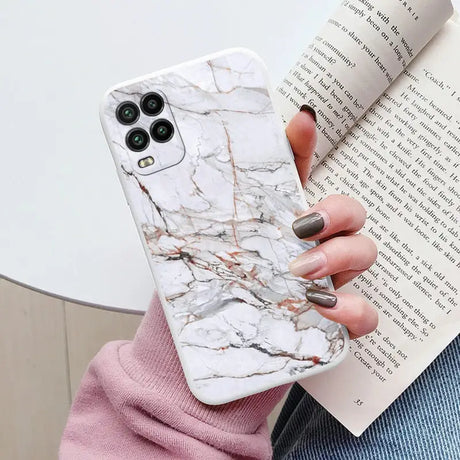 a woman holding a book and a white marble phone case