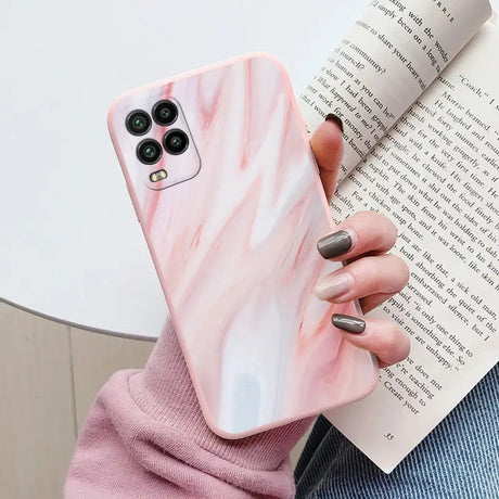 a woman holding a book and holding a pink marble phone case