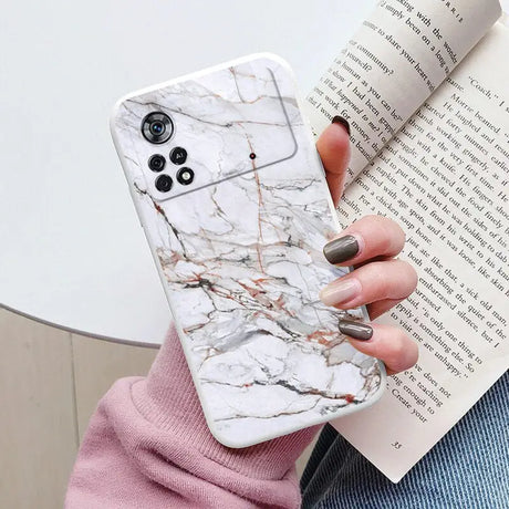 a woman holding a book and a white marble phone case