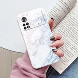 someone holding a book and a phone case with a marble design
