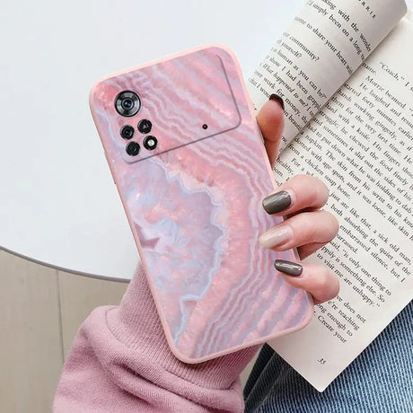 a woman holding a pink marble phone case