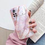 a woman holding a pink marble phone case