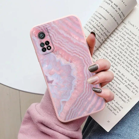 a woman holding a pink marble phone case