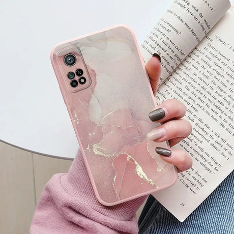 a woman holding a book and a pink marble phone case