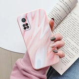 a woman holding a book and holding a pink marble phone case