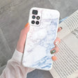 a woman holding a white marble phone case