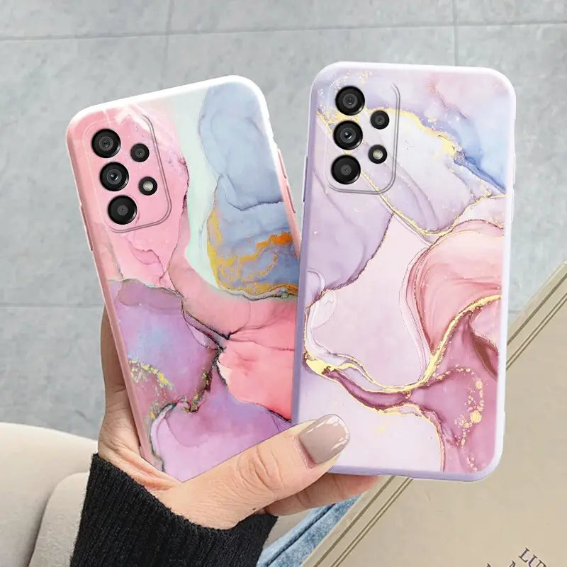 a woman holding two iphone cases with pink and blue marble