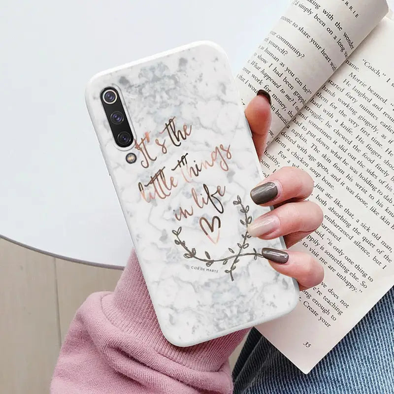 someone holding a book and a phone case with a quote