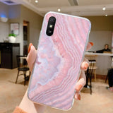 a woman holding up a pink marble phone case