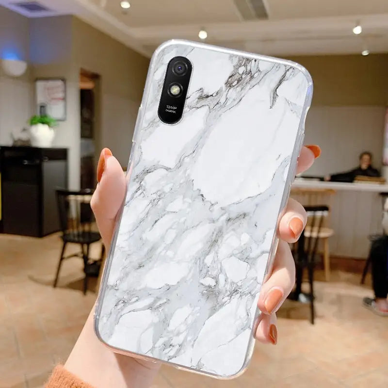 a woman holding a white marble phone case