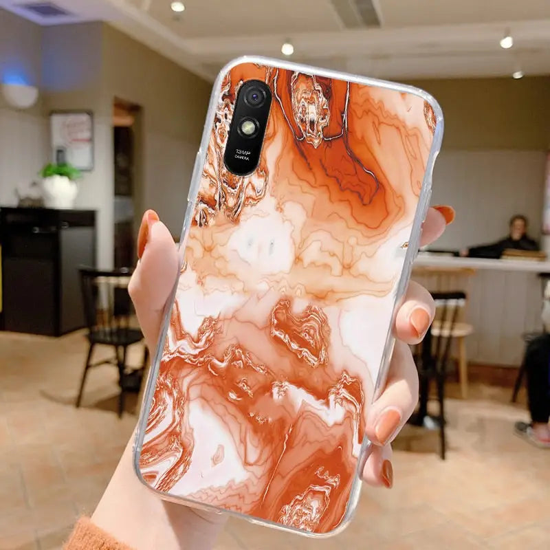 a woman holding up a phone case with a marble pattern