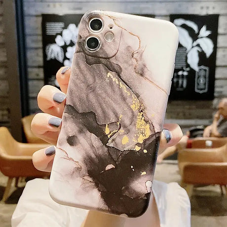 a woman holding up a phone case with a marble pattern