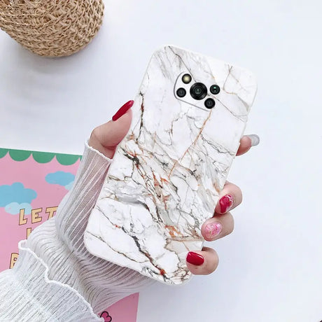 a woman holding a phone case with marble pattern