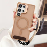 A matte beige smartphone case with a rose gold camera bezel, a built-in magnetic ring, a brown finger strap, and a beige lanyard.