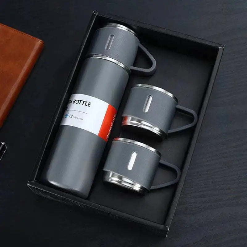 a black box with two stainless coffee mugs and a leather case