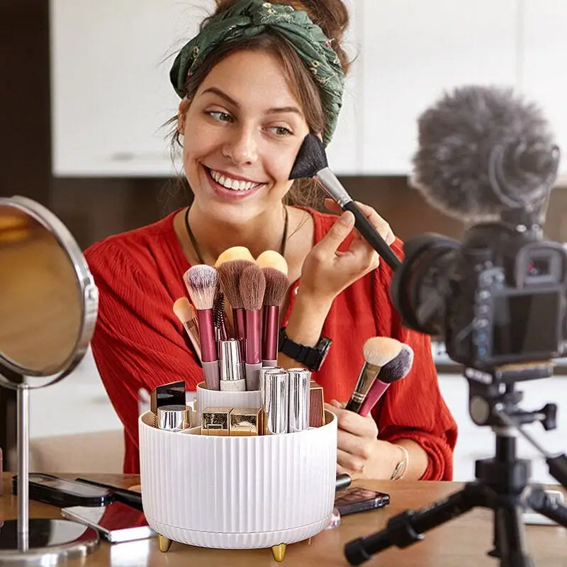 a woman sitting at a table with makeup brushes