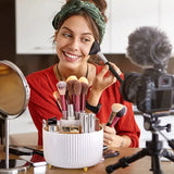 a woman sitting at a table with makeup brushes