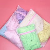 a close up of a bag of clothes on a pink surface