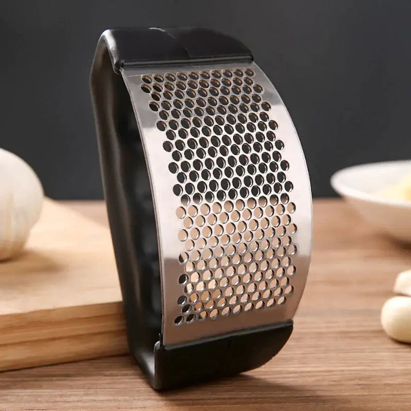 there is a metal grater with a bunch of garlic on it