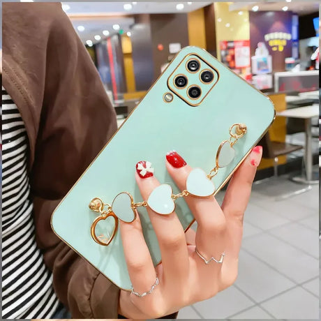 Mint green smartphone case with decorative gold charms attached.